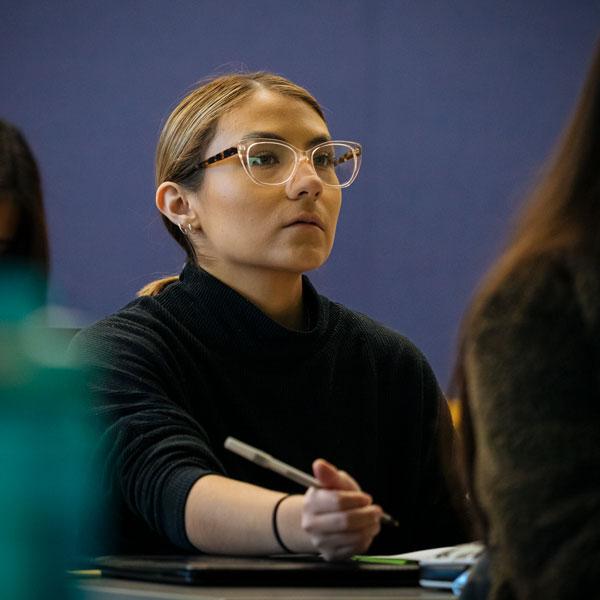 An Agnes Scott public 健康 major student takes notes during a lecture.