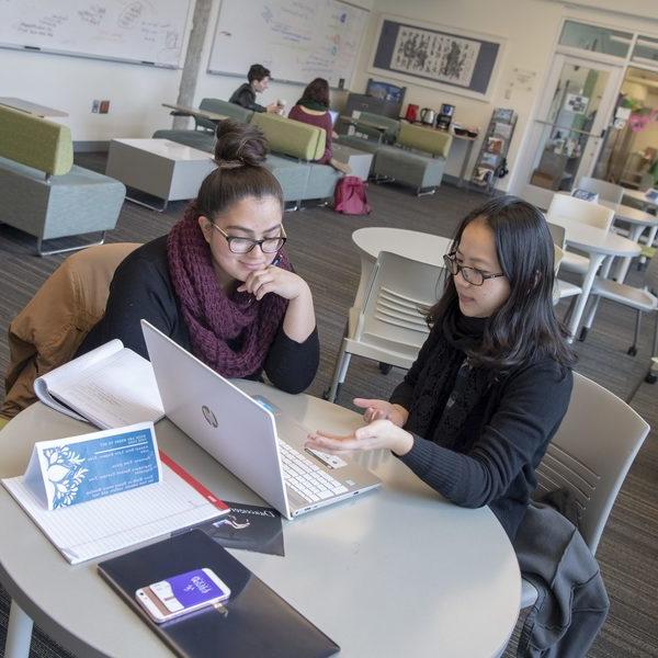 two female students working together in front of a laptop computer